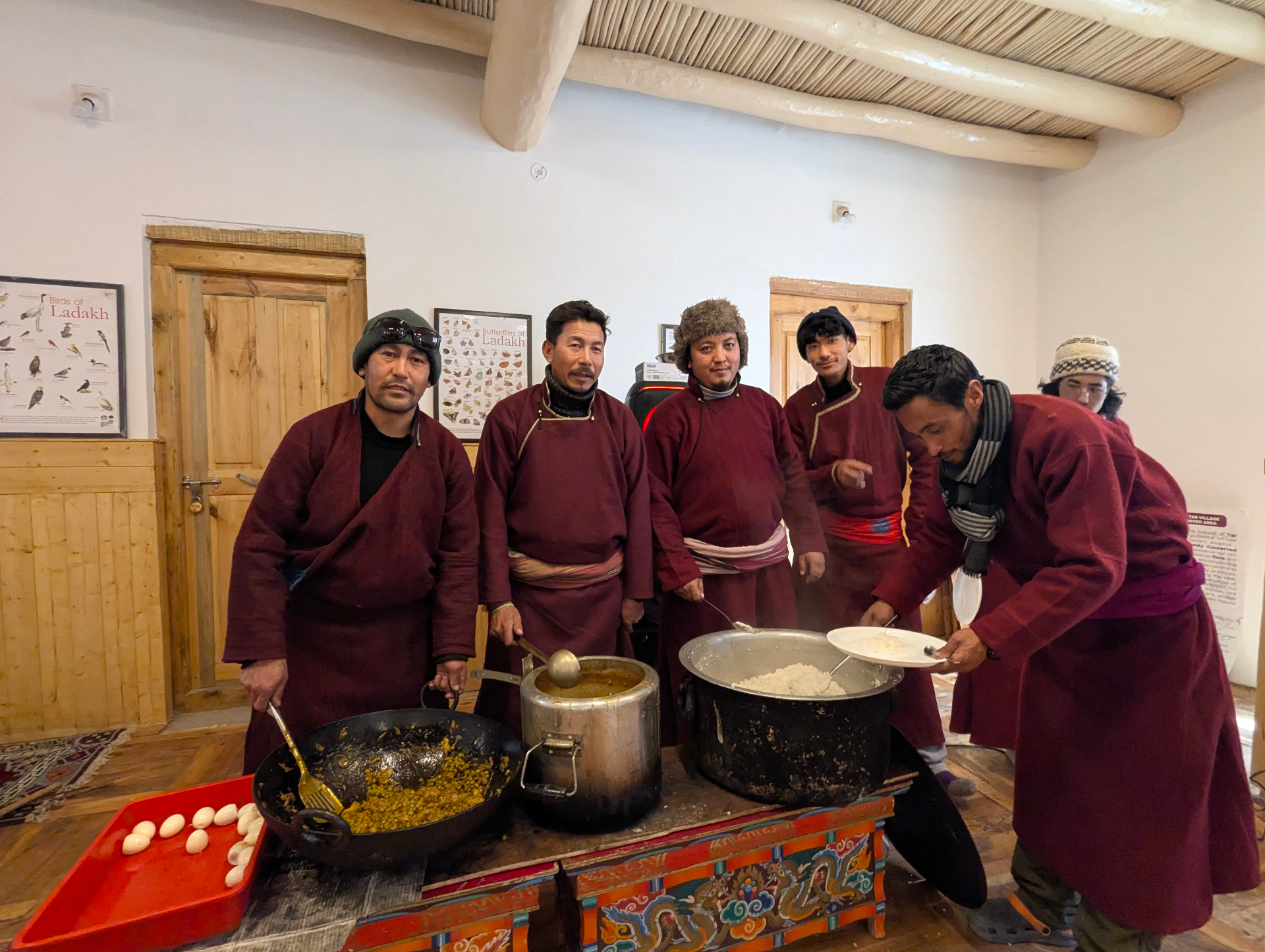 Tar hosts in maroon goncha serving traditional Ladakhi rice and curry