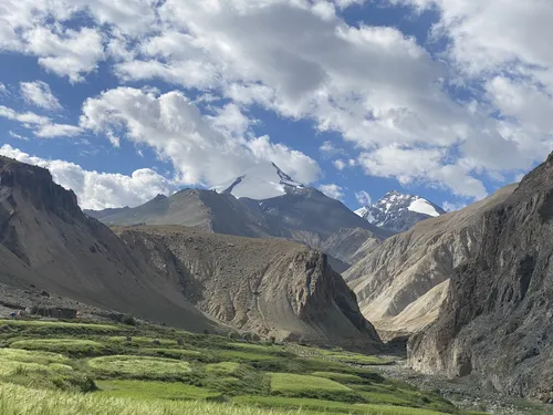 Green fields beneath snow-topped peaks